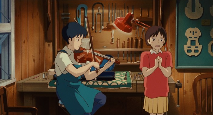 In a luthier's workshop, a boy plays violin and looks on while a girl sings.